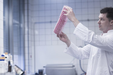 Wissenschaftlerin hält einen Stapel Petrischalen im Labor hoch - CUF22588