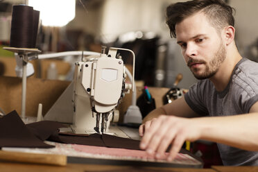 Man using sewing machine to sew leather in leather jacket manufacturers - CUF22629