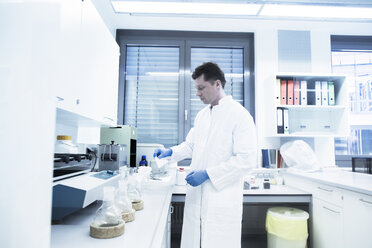 Scientist examining sample inside beaker in laboratory - CUF22644