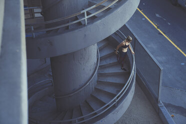 Young woman stretching on spiral staircase outdoors - ISF08258