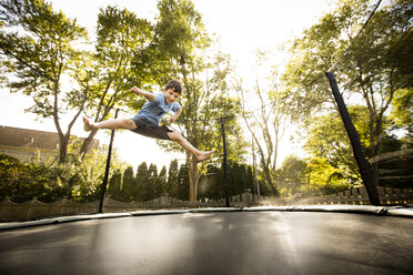 Young boy jumping on large trampoline, low angle view - ISF08276