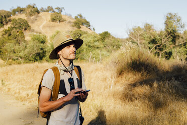 Wanderer hält Smartphone und schaut weg, Malibu Canyon, Kalifornien, USA - ISF08283