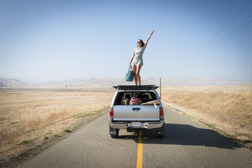 Woman standing on car roof, Highway 1, California, USA - ISF08286