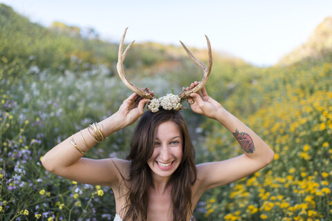 Frau setzt Hörner in einem Wildblumenfeld auf, lizenzfreies Stockfoto