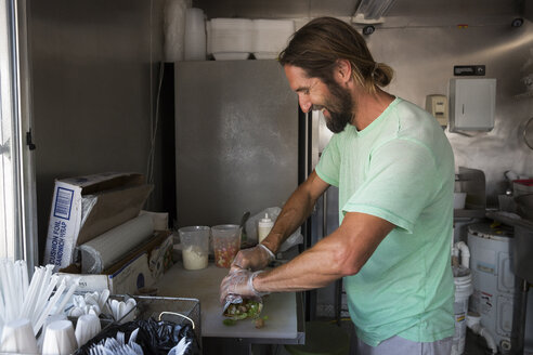 Man preparing order in fast food trailer - ISF08299