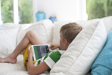 Boy lying on sofa using digital tablet - ISF08310