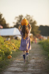 Junges Mädchen, das einen ländlichen Weg entlanggeht und einen Kürbis auf dem Kopf trägt, Rückansicht - ISF08331