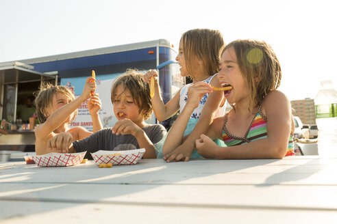 Gruppe von Kindern, die neben einem Fast-Food-Anhänger Fast-Food essen - ISF08336