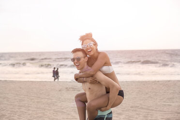 Junger Mann gibt seiner Freundin am Rockaway Beach, New York State, USA, ein Huckepack - ISF08359