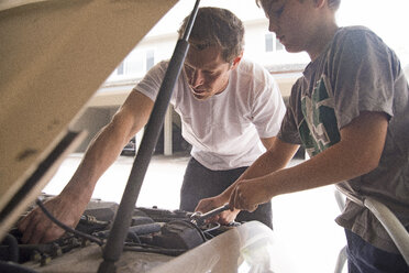 Father showing son car maintenance under car hood - ISF08408