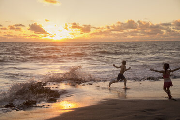 Mädchen und Bruder laufen bei Sonnenaufgang am Strand, Blowing Rocks Preserve, Jupiter Island, Florida, USA - ISF08424