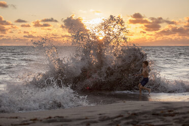 Junge spielt in plätschernden Wellen bei Sonnenaufgang, Blowing Rocks Preserve, Jupiter Island, Florida, USA - ISF08425