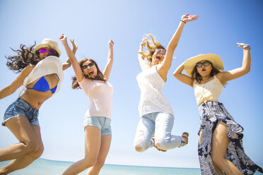 Four adult female friends jumping mid air on beach, Malibu, California, USA - ISF08430