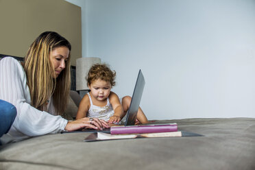 Mutter benutzt Laptop auf Bett mit Tochter - ISF08440