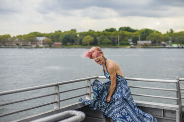 Mature woman standing on boat, laughing, wind blowing dress - ISF08449