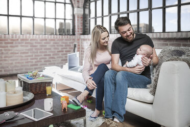 Mother and father sitting on sofa with baby girl - ISF08538