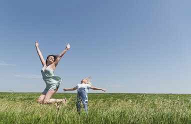 Mother and son jumping for joy in field - ISF08565