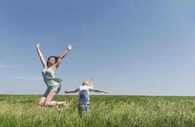 Mutter und Sohn springen vor Freude auf einem Feld - ISF08565