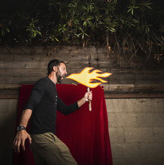 Man holding cardboard cut-out of flames pretending to breathe fire - ISF08610