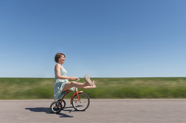 Seitenansicht einer Frau auf einem Dreirad in einer ländlichen Gegend - ISF08625