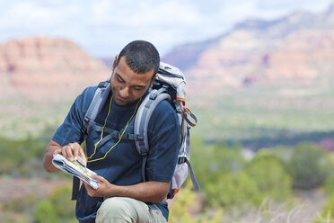 Junger männlicher Wanderer mit Blick auf eine Karte, Sedona, Arizona, USA - ISF08639