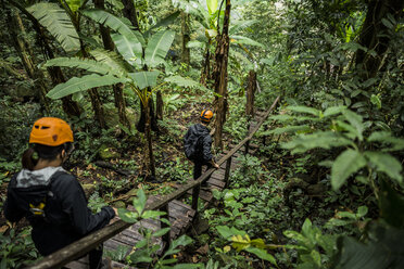 Wanderer überqueren eine Holzbrücke im Wald, Ban Nongluang, Provinz Champassak, Paksong, Laos - ISF08687