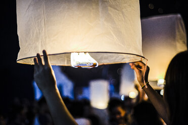 Junge Frau hält eine brennende Papierlaterne in der Hand und wartet darauf, sie beim Loy Krathong Paper Lantern Festival in Chiang Mai, Thailand, loszulassen - ISF08720