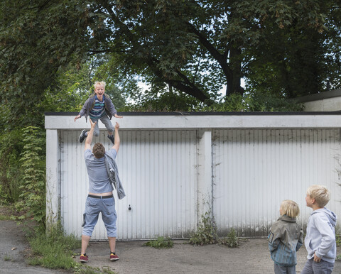 Junge springt von der Garage in die offenen Arme des Vaters, lizenzfreies Stockfoto