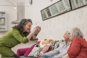 Glückliche Senioren beim Fotografieren auf der Couch - CUF22763