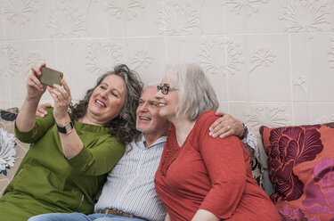 Glückliche Senioren machen ein Selfie auf der Couch - CUF22764