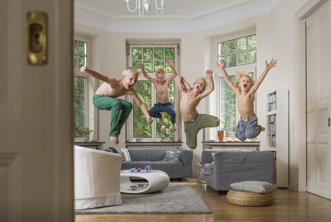 Boys in living room jumping in mid air stock photo