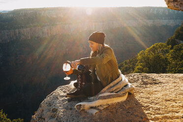 Woman pouring glass of wine on edge of Grand Canyon, Arizona, USA - ISF08779