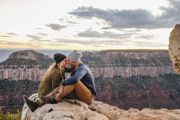 Couple sitting nuzzling on edge of Grand Canyon, Arizona, USA - ISF08782