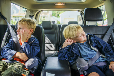 Zwillingsbrüder sitzen gelangweilt auf dem Rücksitz eines Fahrzeugs - ISF08785