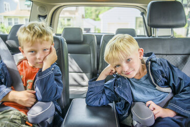 Twin brothers sitting in back of vehicle, bored expressions - ISF08786