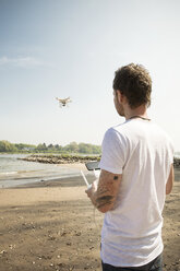 Mann fliegt Drohne an einem Fluss - ONF01142