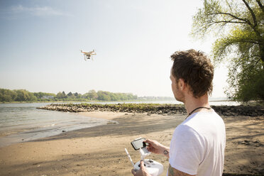 Mann fliegt Drohne an einem Fluss - ONF01143