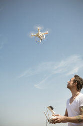 Mann fliegt Drohne unter blauem Himmel - ONF01147