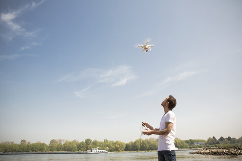 Mann fliegt Drohne an einem Fluss - ONF01148