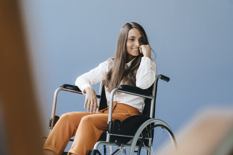 Junge behinderte Frau im Rollstuhl sitzend, lächelnd, lizenzfreies Stockfoto