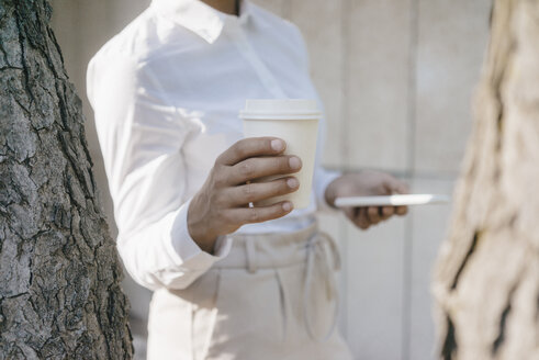 Junge Geschäftsfrau mit einer Tasse Kaffee und einem Smartphone - KNSF03924