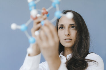 Female scientist holding molecule model, looking for solutions - KNSF03934
