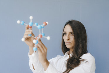 Female scientist holding molecule model, looking for solutions - KNSF03935