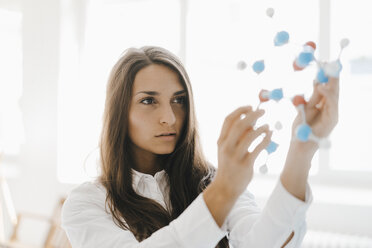 Female scientist holding molecule model, looking for solutions - KNSF03937