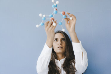 Female scientist holding molecule model, looking for solutions - KNSF03939