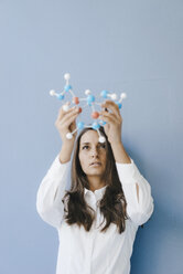 Female scientist holding molecule model, looking for solutions - KNSF03940