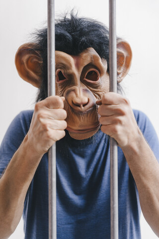 Mann mit Affenmaske hinter Gittern, lizenzfreies Stockfoto