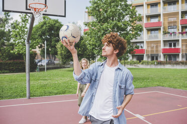 Mann balanciert Basketball, Freundin im Hintergrund - CUF22833