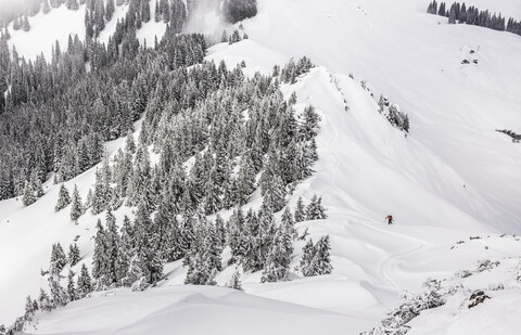 Entfernte Ansicht eines männlichen Skifahrers beim Bergaufgehen am Kranzegg, Bayern, Deutschland, lizenzfreies Stockfoto