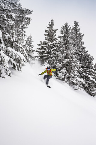 Mann fährt mit dem Snowboard einen steilen Berghang hinunter in Kranzegg, Bayern, Deutschland, lizenzfreies Stockfoto